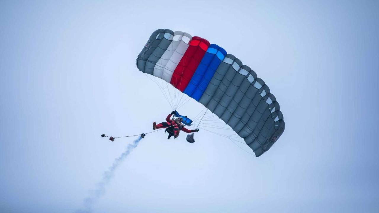 WHA parachute demonstration jumper carrying a flag with smoke